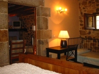 Habitaci doble amb llit indivicual de La Pahissa amb portes en pedra i sostres amb vigues de fusta.