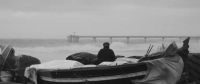 Pescador a la platja de Badalona i el pont del petroli.